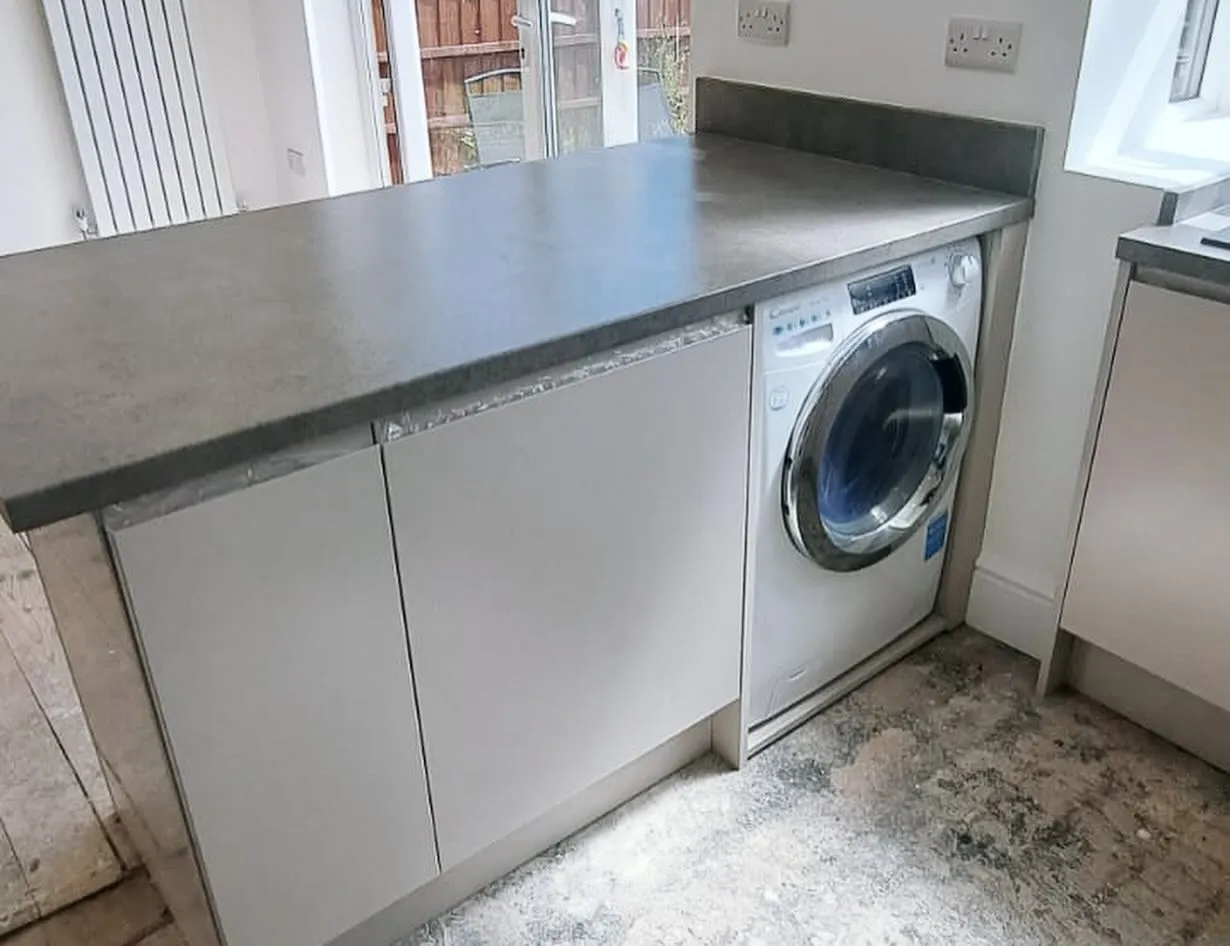 Grey worktop over integrated appliance housing in a light neutral kitchen in Wigan